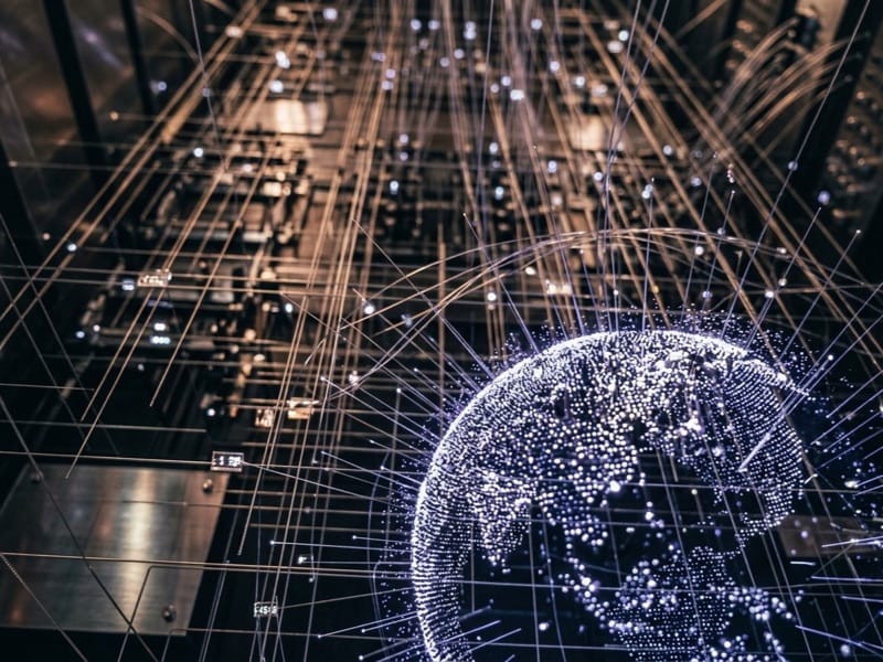 Glowing globe of dotted lights surrounded by criss-crossing light trails over dark circuitry