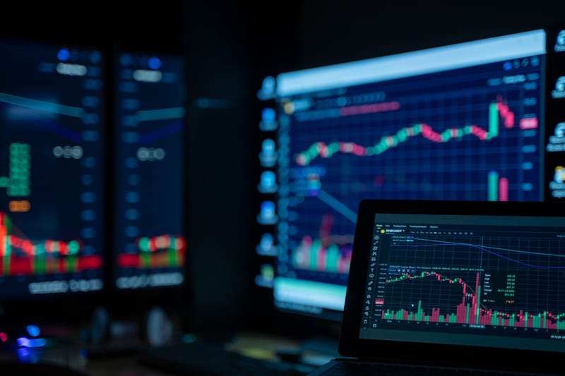 Monitors showing stock market charts in a dimly lit trading room