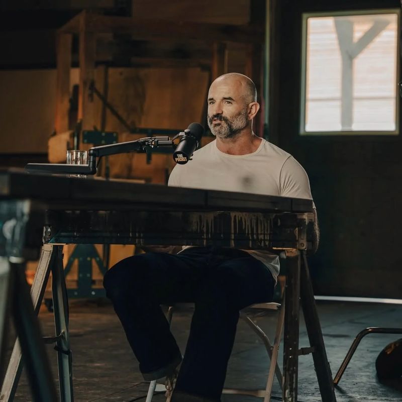 Chris Petkas at the microphone recording a podcast episode in a barn studio